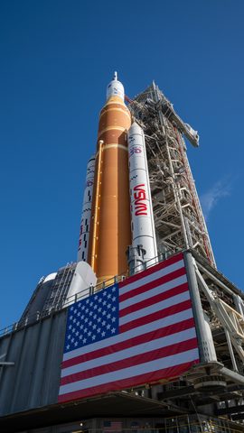 Artemis II SLS rolls out beside the flag